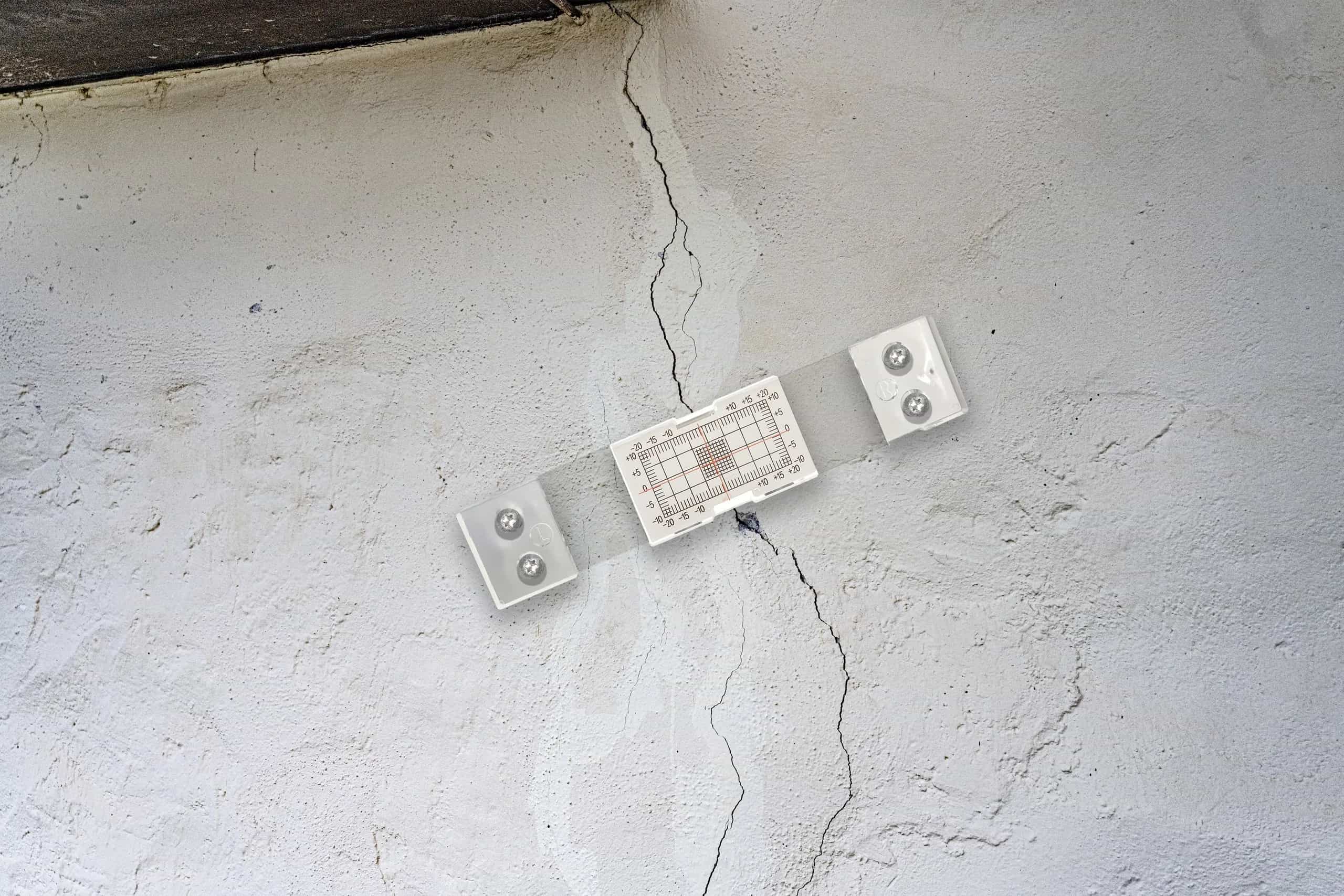 Risssiegel mit Messraster über einem Riss in einer verputzten Fassade